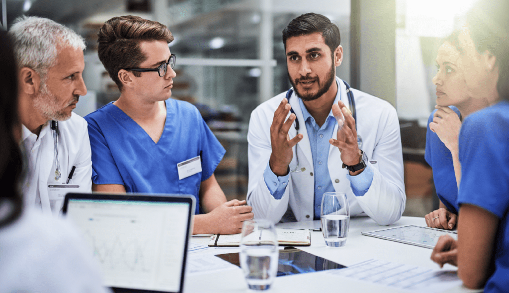 Medical team engaged in a discussion around a table, led by a doctor explaining a concept