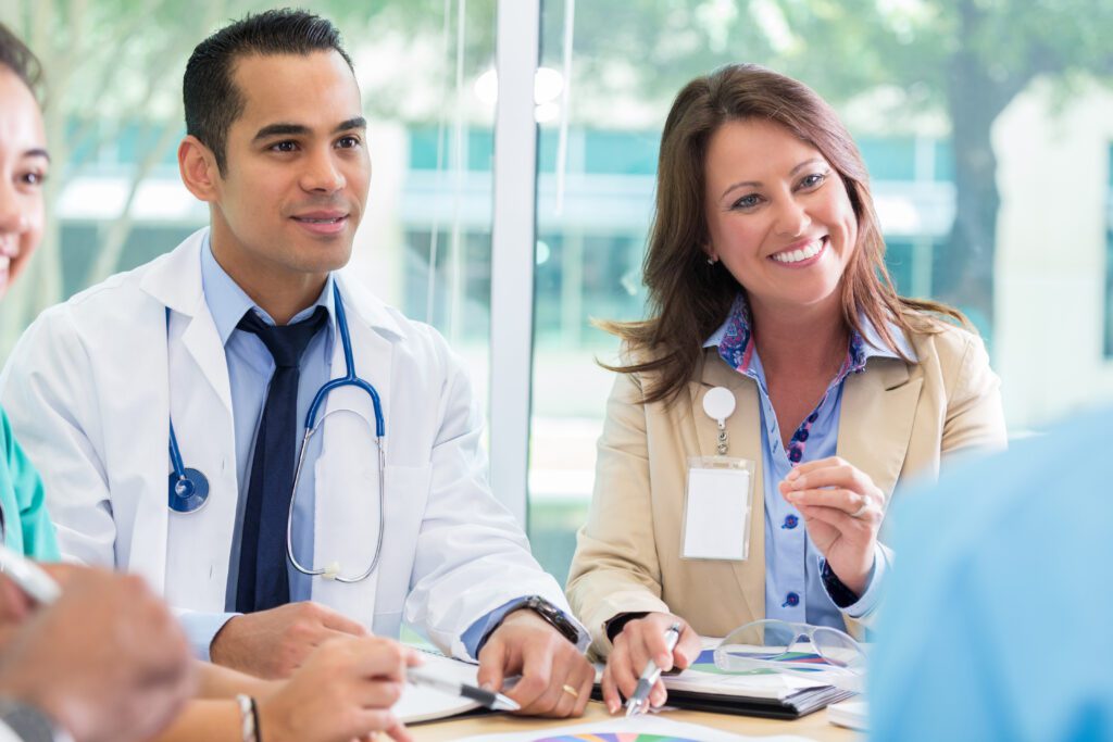 Doctor and healthcare professional smiling during a collaborative meeting, reflecting teamwork