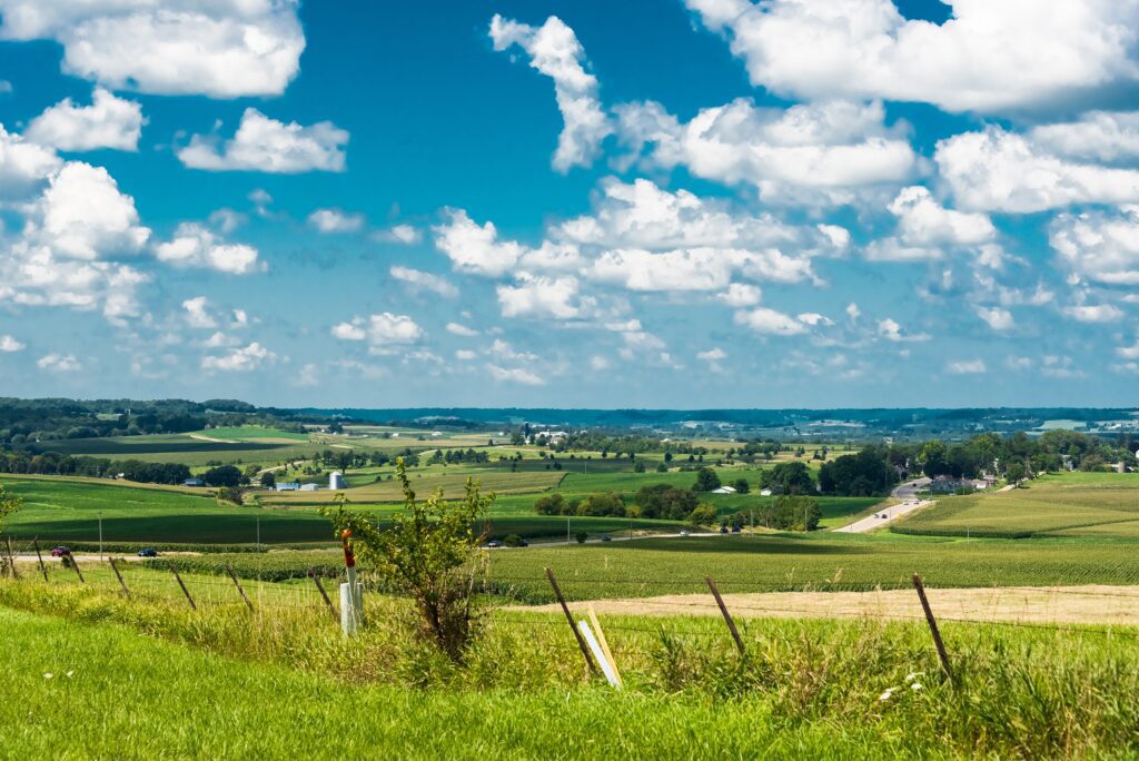 Wide view of a rural landscape with green fields and scattered farms