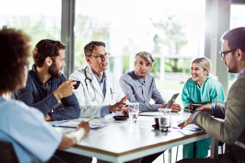 Group of doctors talking while sitting at a table in the office of the hospital