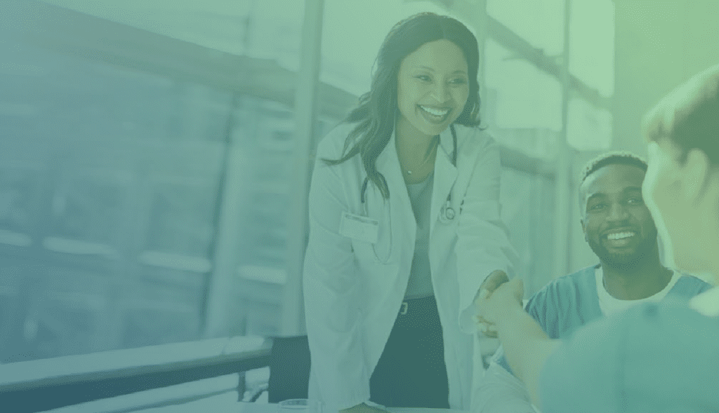 Female doctor smiling and shaking hands with another doctor at a meeting