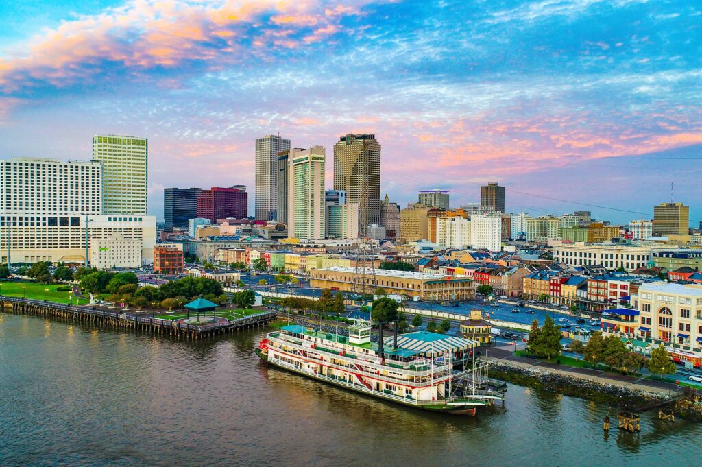 Aerial view of New Orleans skyline at sunset with a riverboat