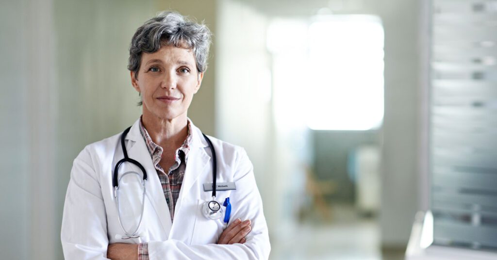 Aged female doctor standing at the clinic