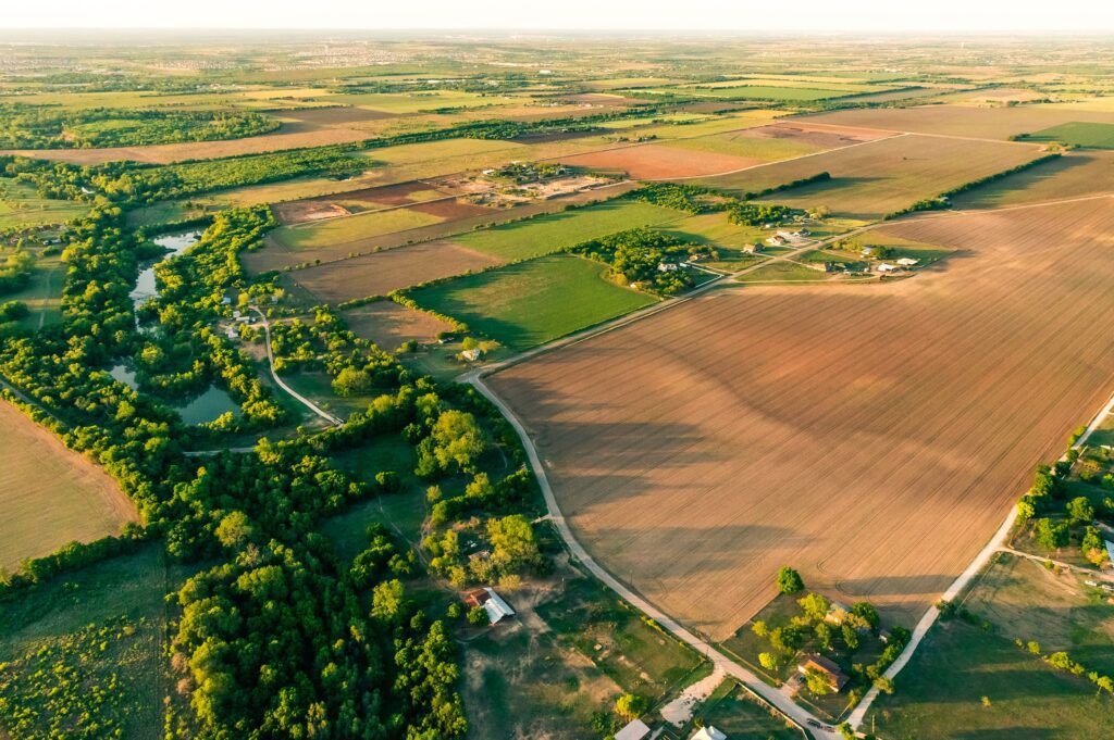 Aerial view of a rural landscape with farmland, scattered houses, and patches of trees