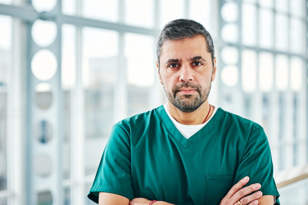 Serious looking male doctor wearing green scrubs