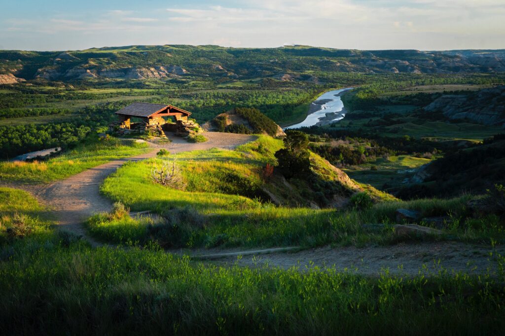 Scenic view of a cabin overlooking a river winding through lush, green hills at sunset