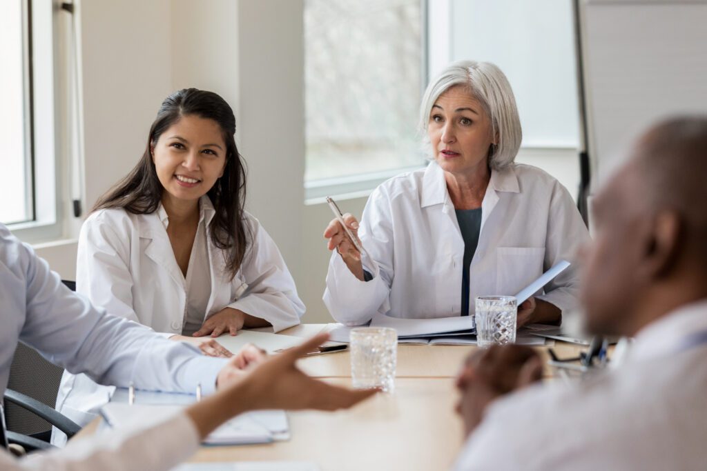 Team of healthcare workers in boardroom with female doctor presenting her plan