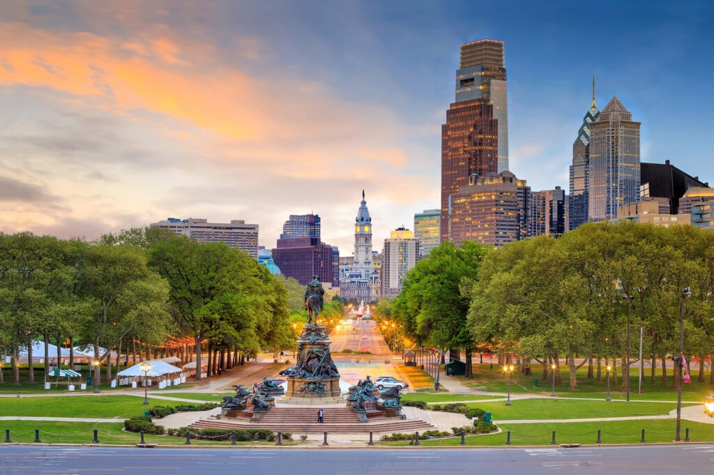 A cityscape at sunset with iconic statues and skyscrapers