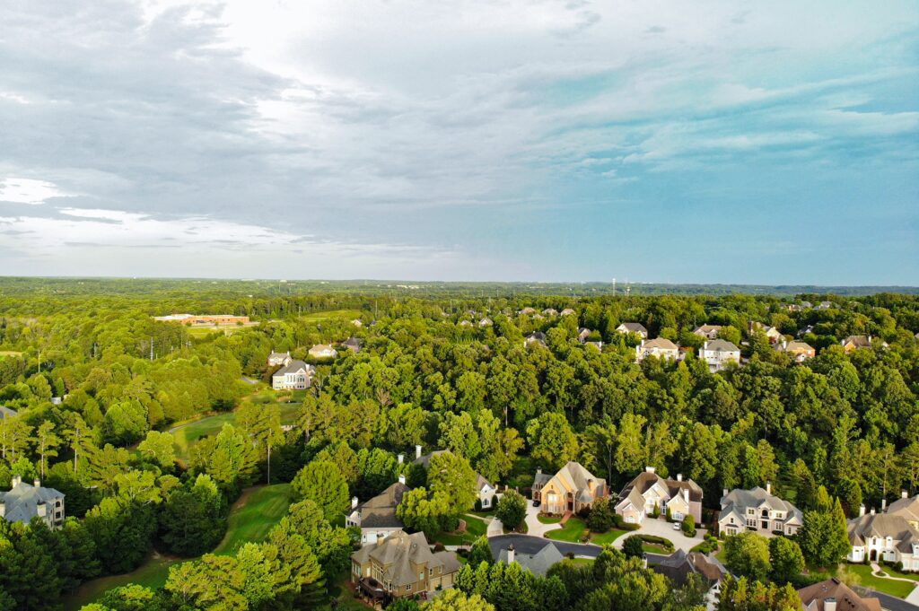 Aerial view of a suburban neighborhood surrounded by dense green trees