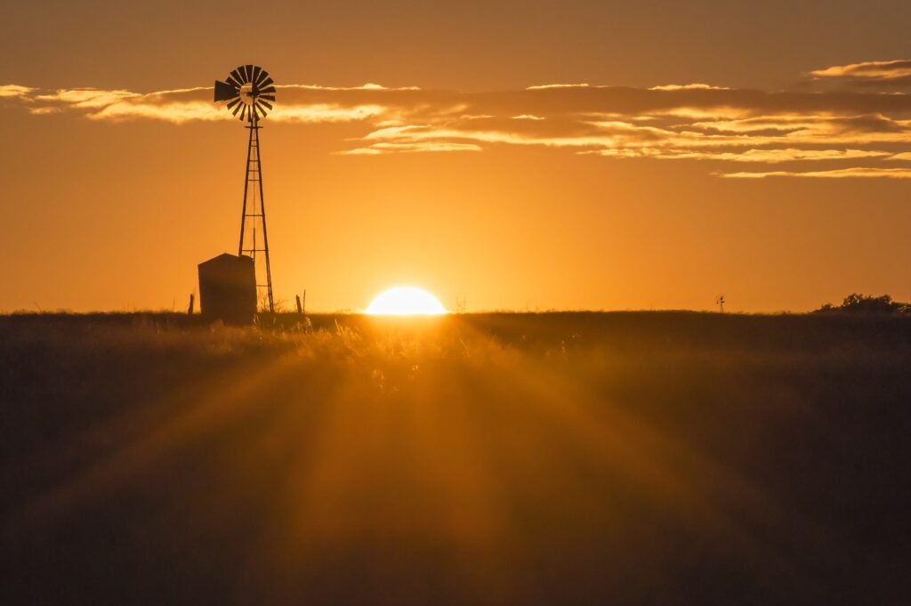 Sunset behind a silhouette of a windmill in a vast, golden field