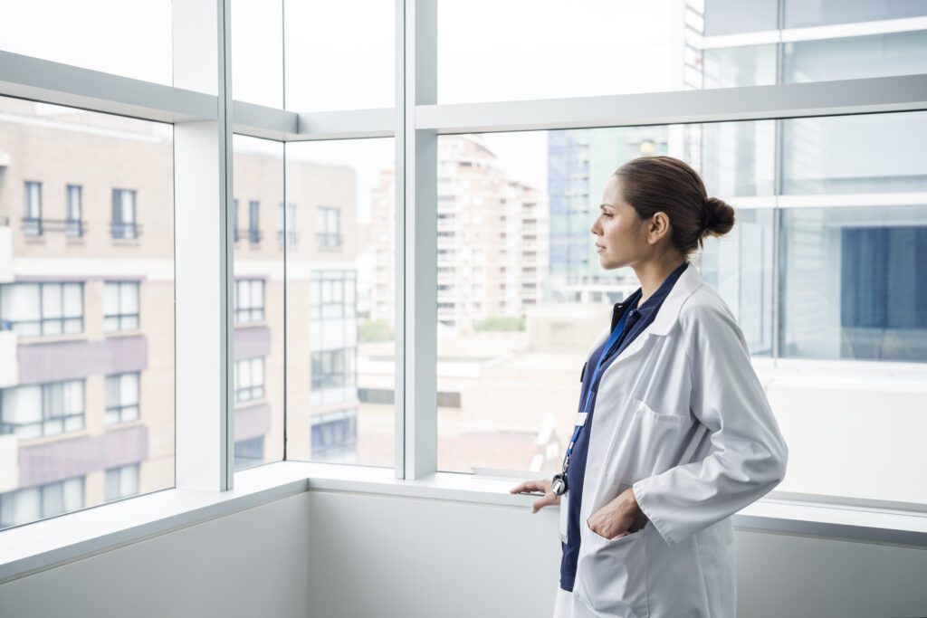 Doctor standing by a window, looking out at the cityscape