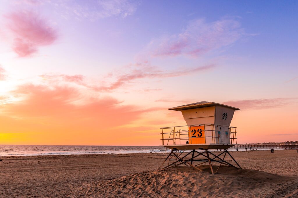 A lifeguard tower marked with the number 23 on a beach in front of a sunset sky