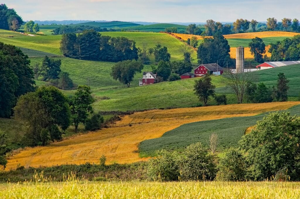 Scenic farmland with rolling hills, red barns, and green fields