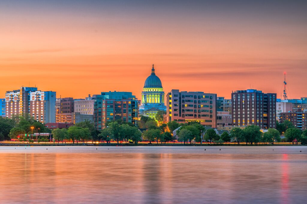 City skyline at sunset with a domed building and water in the foreground