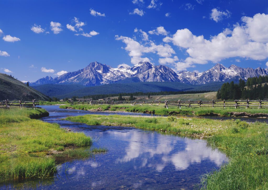 A serene mountain landscape with a clear blue sky, snow-capped peaks