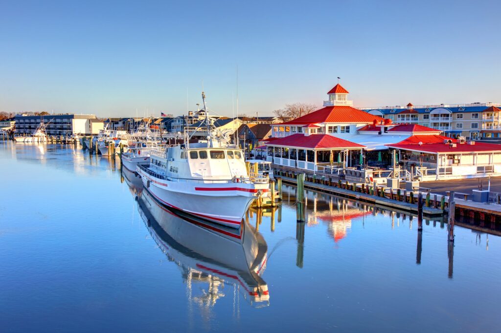 Fishing boat docked at a vibrant marina with colorful buildings and clear blue skies