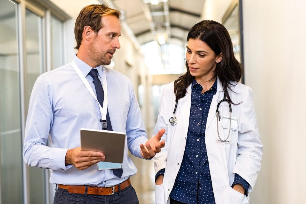 Healthcare administrator with a tablet discussing with a doctor in a hospital