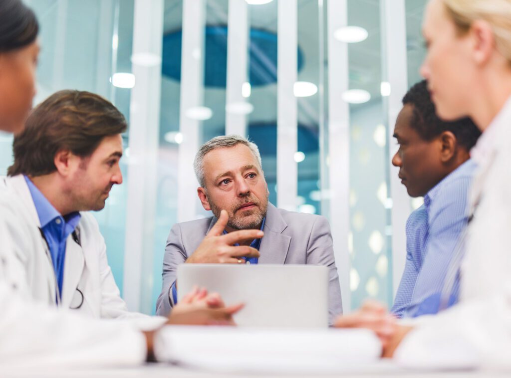 Middle-aged man discussing with a group of doctors in a modern office