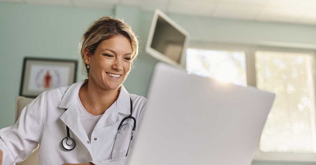 Smiling female doctor using a laptop in a hospital