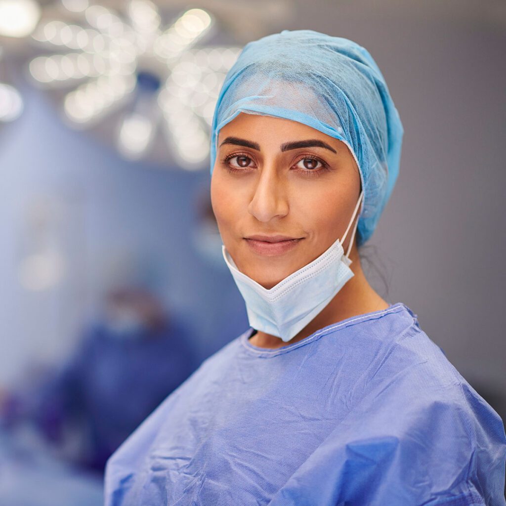 Confident female surgeon in blue scrubs and a mask in a well-lit operating room