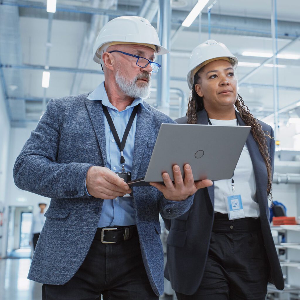 Two people wearing hard hats walking around a facility