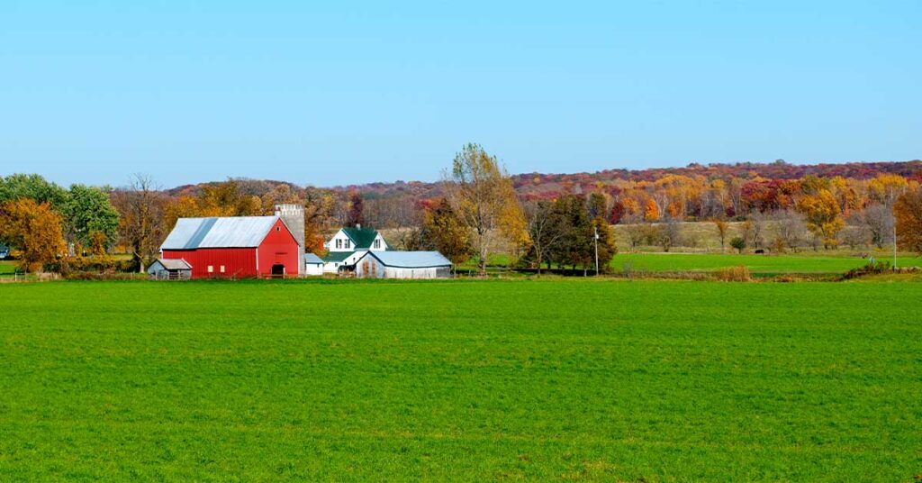 Rural landscape with a red barn, white farmhouse, and green fields