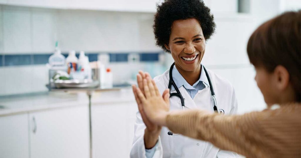 smiling doctor shares a high five with a young patient