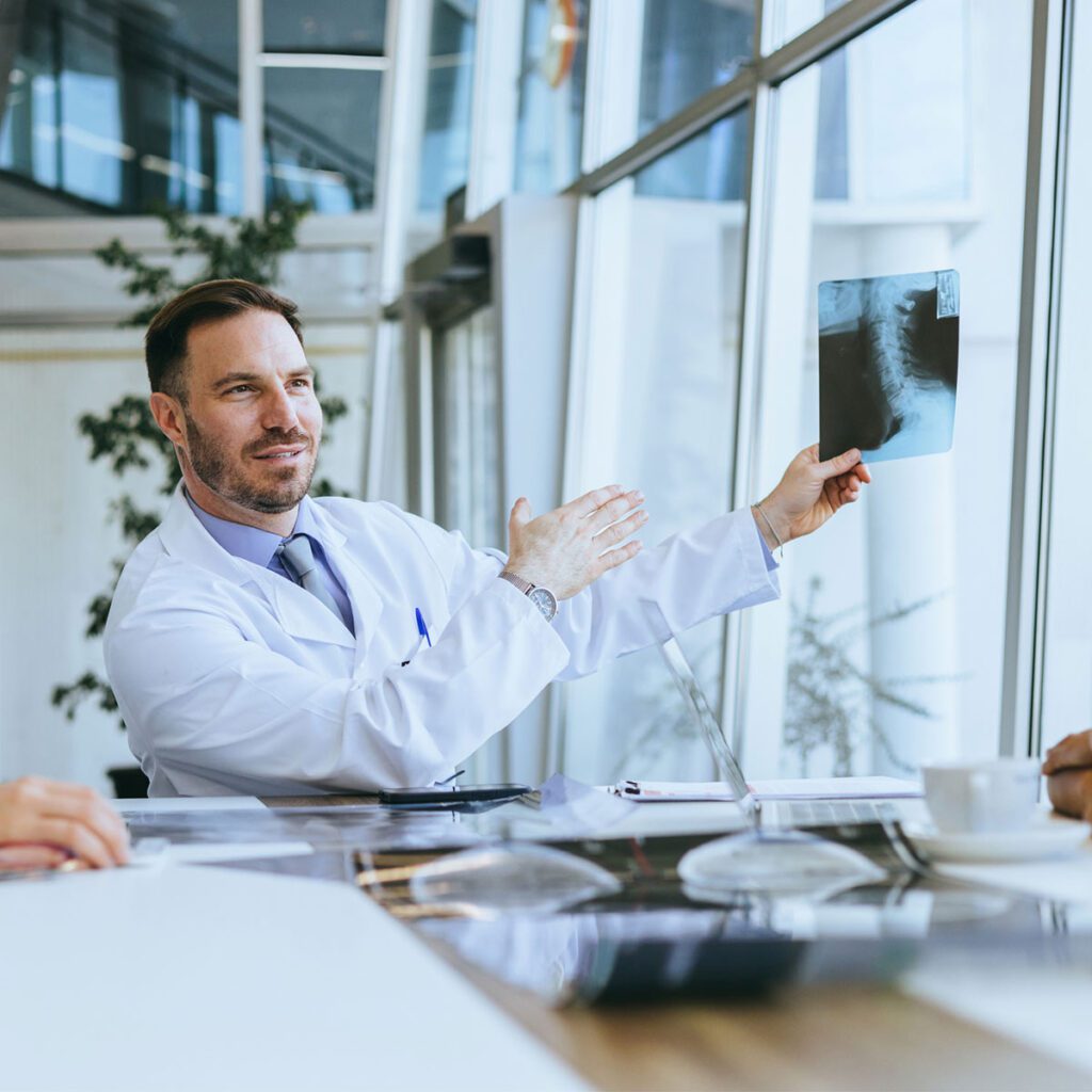 Doctor in a white coat presenting an X-ray during a discussion in a modern office